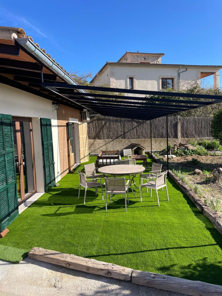 Patio trasero con césped sintético de bajo mantenimiento