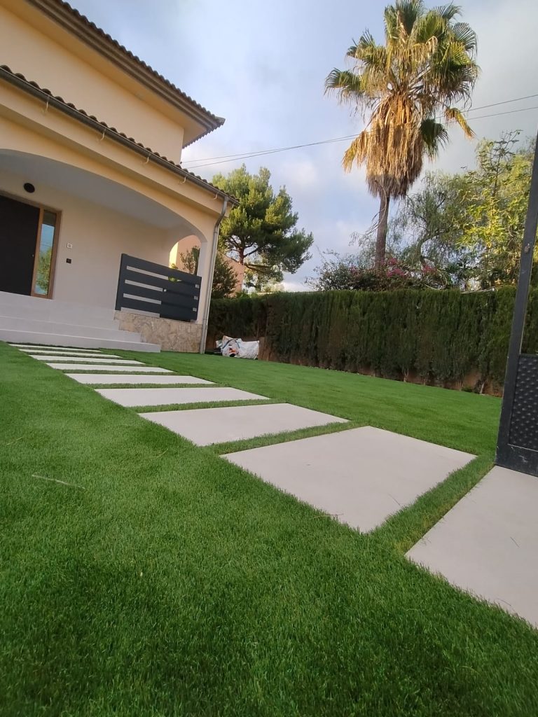 Entrada de casa moderna con losas rectangulares sobre césped artificial perfectamente colocado