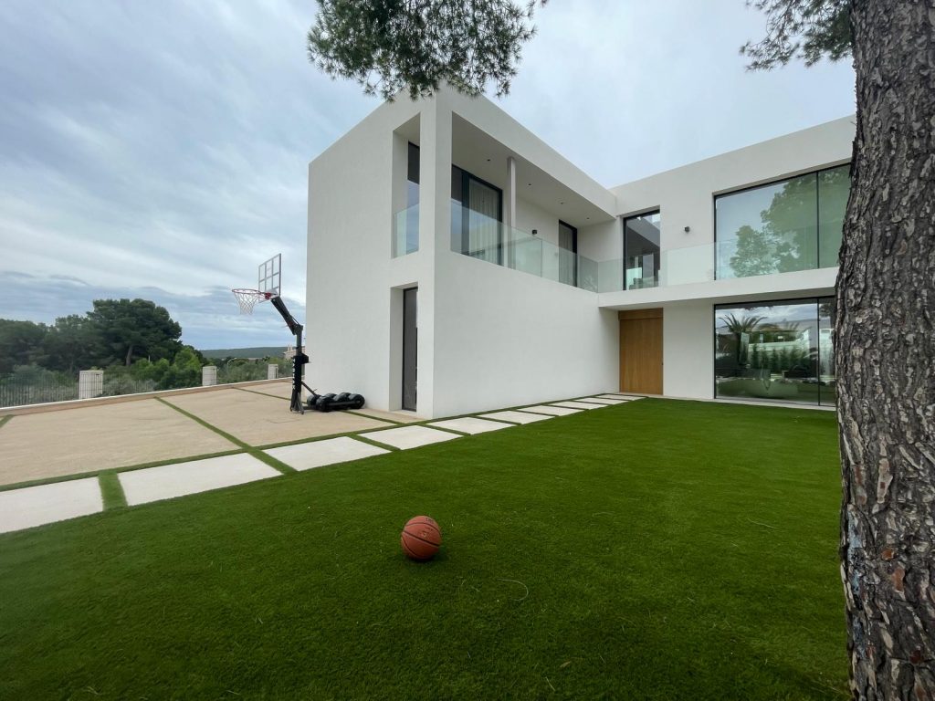 Vivienda con césped artificial y diseño de jardín moderno.